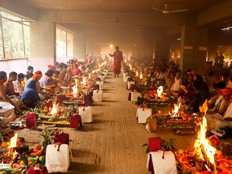 A vibrant and colorful Hindu ritual with participants in traditional attire and ceremonial fires in Dhaka.